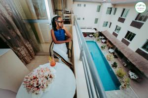 a woman sitting on a balcony with a drink at City Hill Hotel in Bujumbura