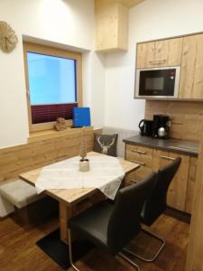 eine Küche mit einem Holztisch mit Stühlen und einem Fenster in der Unterkunft Haus Bergjuwel in Huben