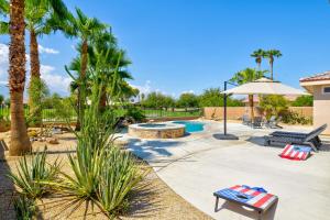 a pool with palm trees and benches and an umbrella at Palms Place in Indio in Indio