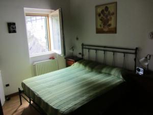 una camera da letto con un letto con un piumone verde e una finestra di Appartamento San Vito a Cremia