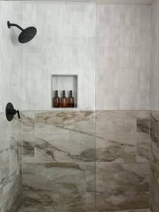 a bathroom with a shower with bottles on a shelf at Casa Wabi on Park Lane in Dallas + 2 King Beds in Dallas