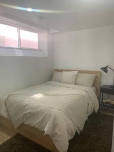 Bett in einem weißen Zimmer mit Fenster in der Unterkunft Cheerful and cozy 1 bedroom,separate entrance in Winnipeg