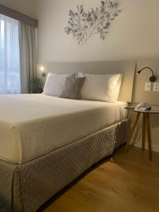 a bedroom with a large bed with a side table at Flat Jardins, entre Av Paulista e Parque do Ibiraquera in São Paulo