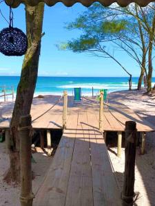 a wooden boardwalk on a beach with the ocean at Chalé Aloha Ihul ! O paraíso pé na areia ! in Arraial do Cabo