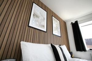 a bedroom with a wooden headboard with two pictures above a bed at 4 Bed Contractor House-Parking-WiFi-Smart Tvs in Each Bedroom-Special Rates Available in Peterborough