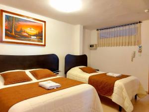 HOSTAL MURGEON BOUTIQUE في كيتو: غرفه فندقيه سريرين عليها مناشف