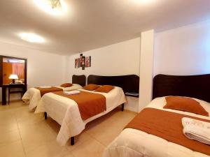 HOSTAL MURGEON BOUTIQUE في كيتو: غرفة في فندق بثلاث اسرة في غرفة
