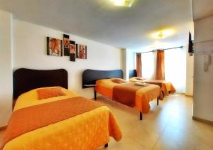 HOSTAL MURGEON BOUTIQUE في كيتو: غرفة في الفندق بسريرين وملاءات برتقالية