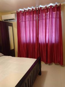 a bedroom with red curtains and a bed in front at Al-ED Homestay in Butuan