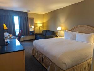 una camera d'albergo con un grande letto e un divano di Nomad Hotel & Suites a Fort McMurray