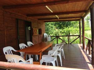 a wooden deck with a wooden table and white chairs at El Descanso in Roldán