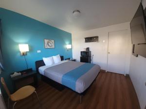 a hotel room with a bed and a blue wall at Othello Inn And Suites in Othello