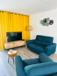 a living room with two blue couches and a television at SAB Location - Appartement in Ducos