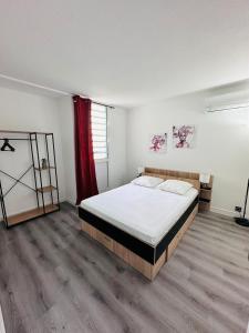 a bedroom with a large bed and a red curtain at SAB Location - Appartement in Ducos