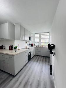 a large white kitchen with white cabinets and a camera at SAB Location - Appartement in Ducos