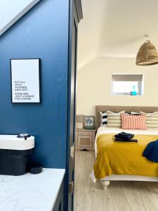 ein Schlafzimmer mit einer blauen Wand, einem Bett und einem Waschbecken in der Unterkunft The Loft Curracloe, on Wexfords Coastal Scenic Route in Wexford