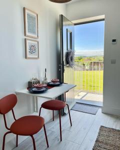 a dining room with a table and two red chairs at The Loft Curracloe, on Wexfords Coastal Scenic Route in Wexford