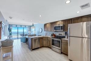 a kitchen with wooden cabinets and a white refrigerator at Ideally situated beachfront condo with pool and views in Marco Island