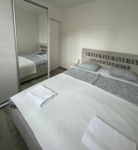 a bedroom with a large white bed and a mirror at Apartman “ Ismar “ in Travnik