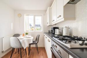 Il comprend une cuisine équipée d'une cuisinière et d'une table avec des chaises. dans l'établissement Grenadier House, à Coventry