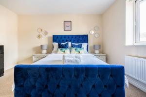 a blue tufted bed in a white bedroom at Grenadier House in Coventry