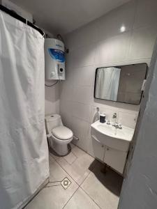 y baño con aseo, lavabo y espejo. en Moderno Monoambiente con estacionamiento en Godoy Cruz