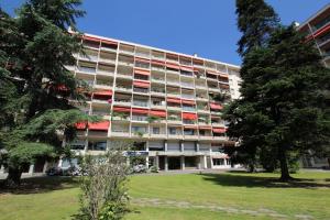 an apartment building with red and white balconies and trees at Residence du parc appt 300 in Bayonne
