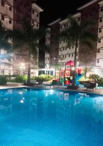 a swimming pool in front of a building at night at Happy Stays A - Sunset View at SMDC Hope Residences in Trece Martires