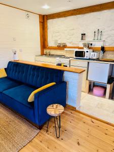 a blue couch in a living room with a kitchen at The annex on our farm in Colwyn Bay