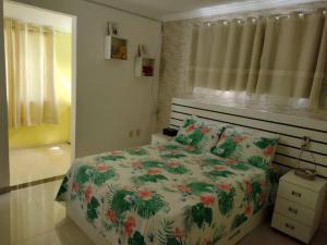 a bedroom with a bed with a floral comforter at Cozy Home Arembepe Beach in Camaçari