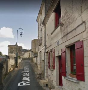 an empty street next to a building with red doors at La Maison du Donjon - Gites de 8 personnes, parking privé avec jardin terrasse in Loches