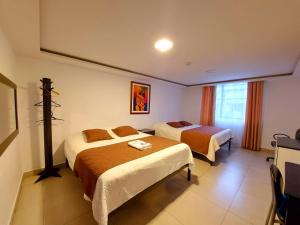 Habitación de hotel con 2 camas y ventana en SIENA Inn HOSTAL, en Quito