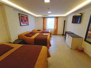 a hotel room with two beds and a television at SIENA Inn HOSTAL in Quito