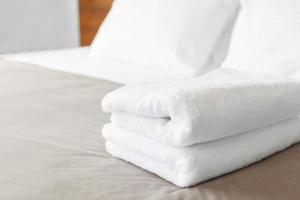 una pila de toallas blancas sentadas en una cama en Pear Tree Inn Cape Girardeau Medical Center, en Cape Girardeau