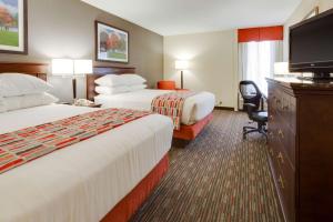 a hotel room with two beds and a flat screen tv at Pear Tree Inn Sikeston in Sikeston