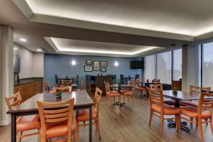 a dining room with tables and chairs and a television at Pear Tree Inn Cape Girardeau West in Cape Girardeau