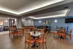 a restaurant with tables and chairs and a flat screen tv at Pear Tree Inn Cape Girardeau West in Cape Girardeau
