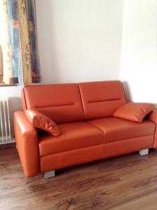 eine orangefarbene Couch mit zwei Kissen in einem Zimmer in der Unterkunft Pension La Mamma in Aschach an der Donau