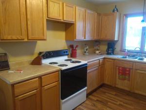 a kitchen with wooden cabinets and a black and white stove at Bass Creek's Cozy Outback Country Retreat in Janesville +11 photos