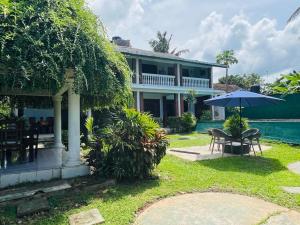 a house with a patio and a table and an umbrella at Little Paradise in Bentota