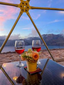 dois copos de vinho e um vaso de flores sobre uma mesa em Pacucha Glamping em Andahuaylas