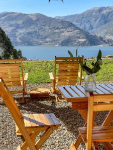 two wooden chairs and a picnic table with a view of a lake at Pacucha Glamping in Andahuaylas