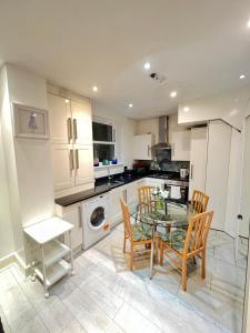 eine Küche mit einem Tisch und Stühlen sowie eine Küche mit weißen Schränken in der Unterkunft Fulham suites in London