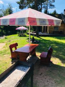 - une table de pique-nique avec un parasol et deux chaises dans l'établissement Artur´s Eaterie and Holiday home, à Viitna