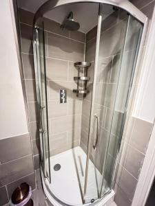 a shower with a glass door in a bathroom at Fulham suites in London