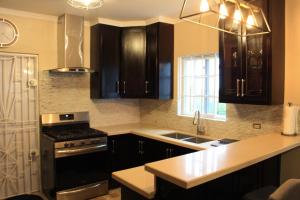 a kitchen with black cabinets and a stove top oven at Soleil Palm View Villa in Priory