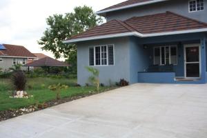 a small blue house with a concrete driveway at Soleil Palm View Villa in Priory