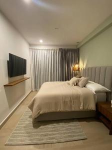 a bedroom with a large bed and a television at Departamento nuevo con vista a la Piscina in Nuevo Vallarta 