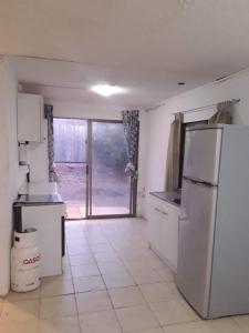 a kitchen with a refrigerator and a door to a yard at Cabaña en Pica con Jacuzzi privado in Pica