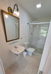 a bathroom with a sink and a toilet and a mirror at Suíte Beach Host - Praia Pernambuco in Guarujá